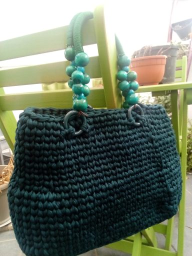 Borsa lavorata a maglia in verde scuro con manici a perle verdi.